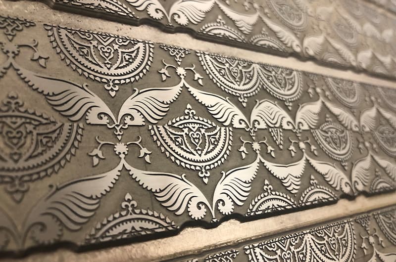 Laser-engraved plate carrying a fine ornamental pattern in close detail