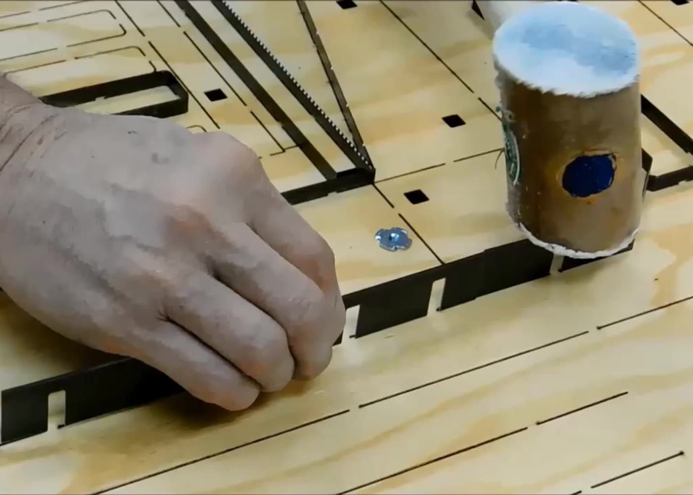 Die maker seating bent steel rule into a board with a mallet