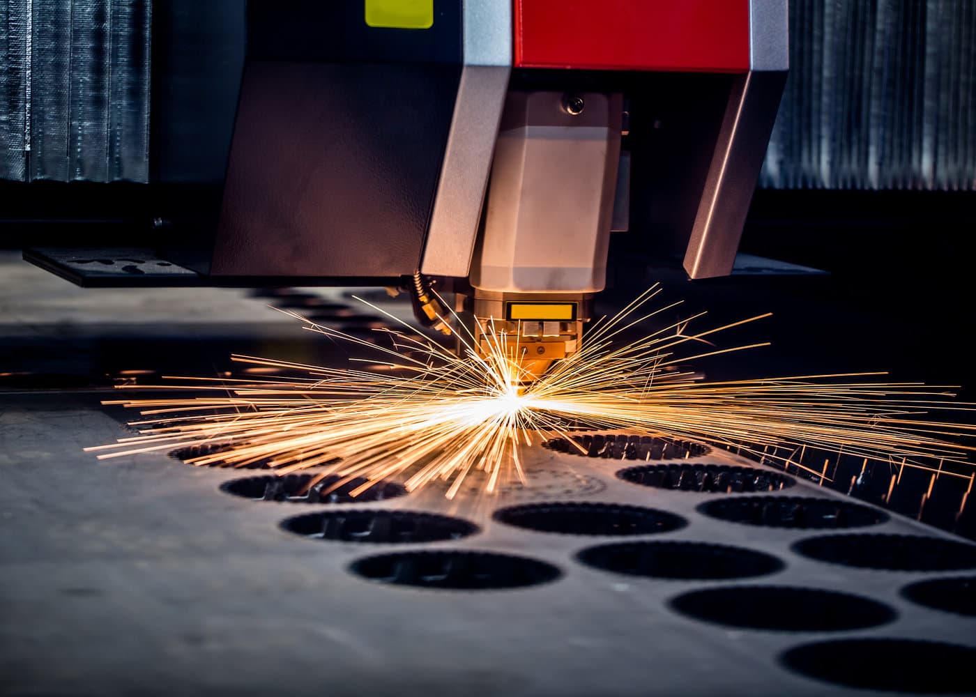 Fiber laser cutting a steel die board, sparks fanning across the bed